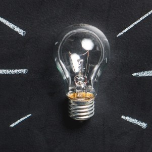 A lightbulb sits on a chalkboard background with white lines coming from it