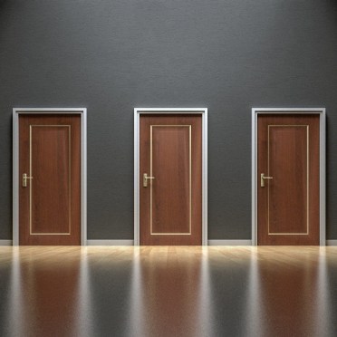 On a grey wall are three identical brown doors