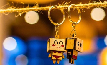 Two happy robot keychains hanging from a piece of string