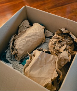 Moving box with paper-wrapped breakables and a sweater in it.