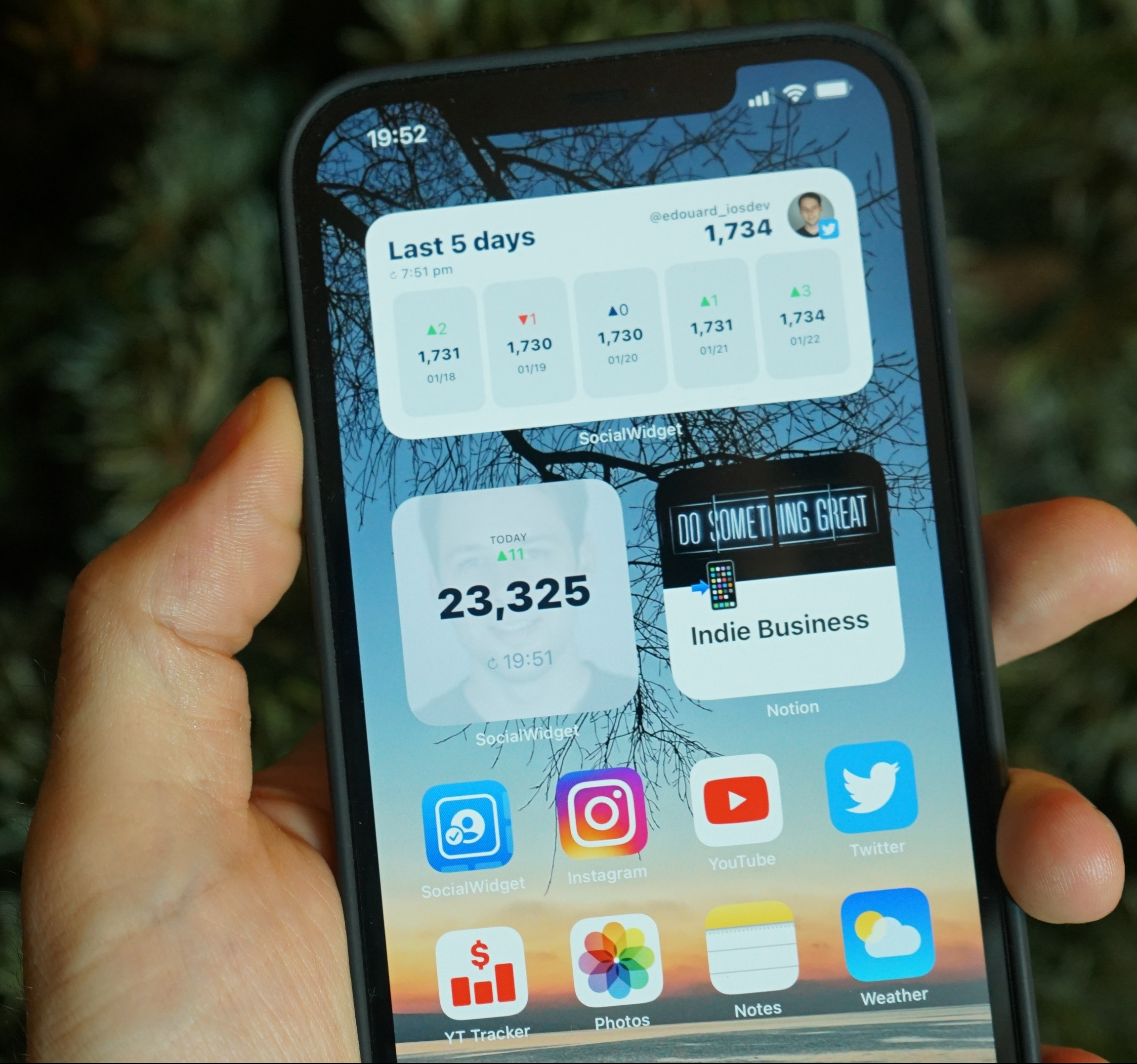 A person is holding a smartphone showing apps and widgets wit numbers, statistics, and metrics