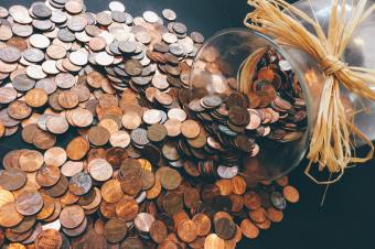 Pennies spilling out of a glass decorative vase onto a black tabletop