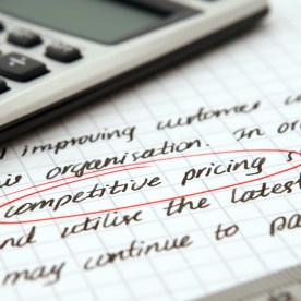 Underneath a calculator there is a page of graph paper with script on it from a lead letter. The words "competitive pricing" are circled in red