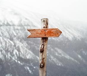 An unlabelled signpost sits on a snowy mountaintop