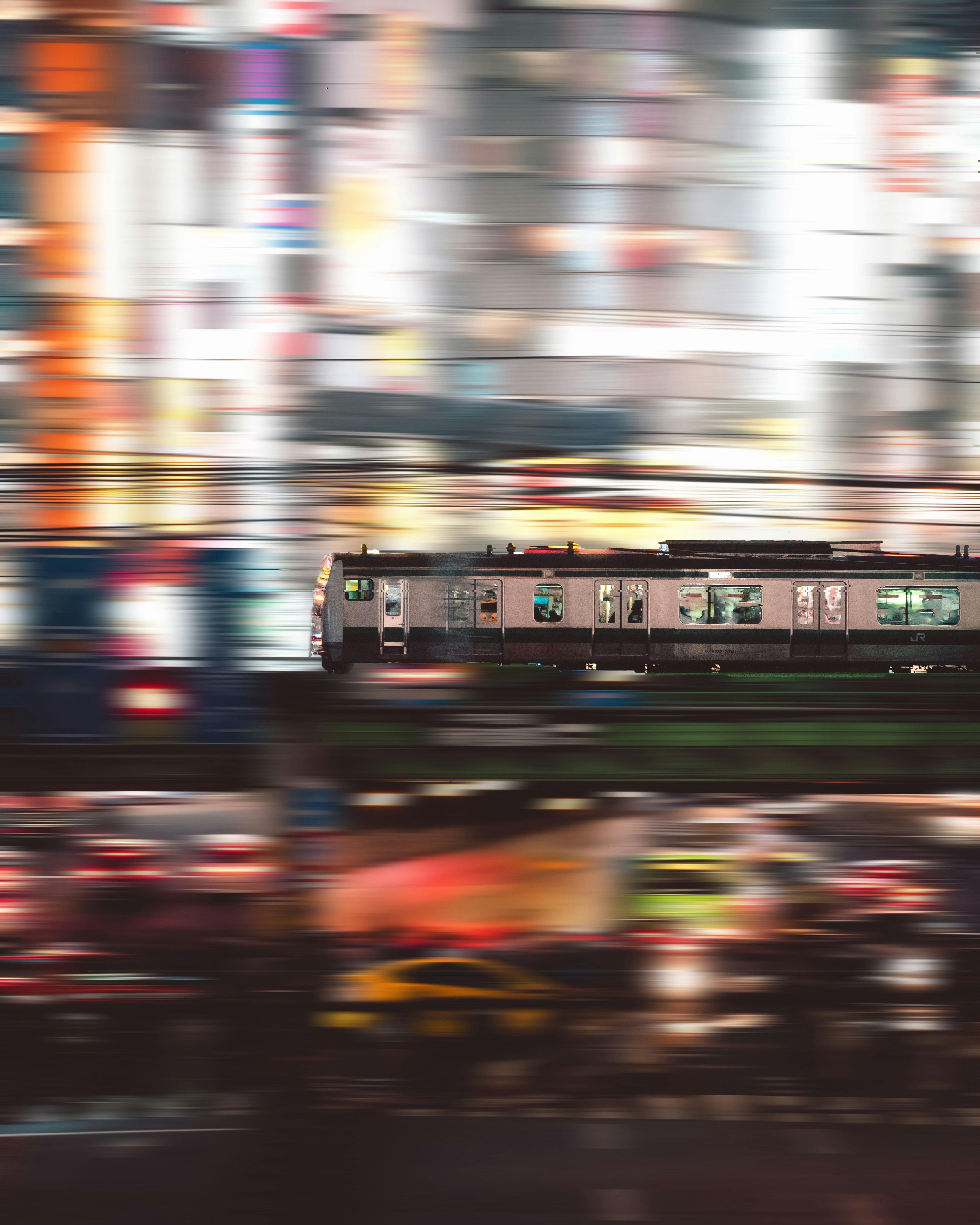 A black and white train rushes past a blurred city.