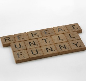 Wooden Scrabble letters on a white background spell out "Repeat until funny".