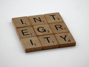 On a white background are 9 scrabble tiles. They are are split into 3 rows of 3 to form a square. They read "INTEGRITY".
