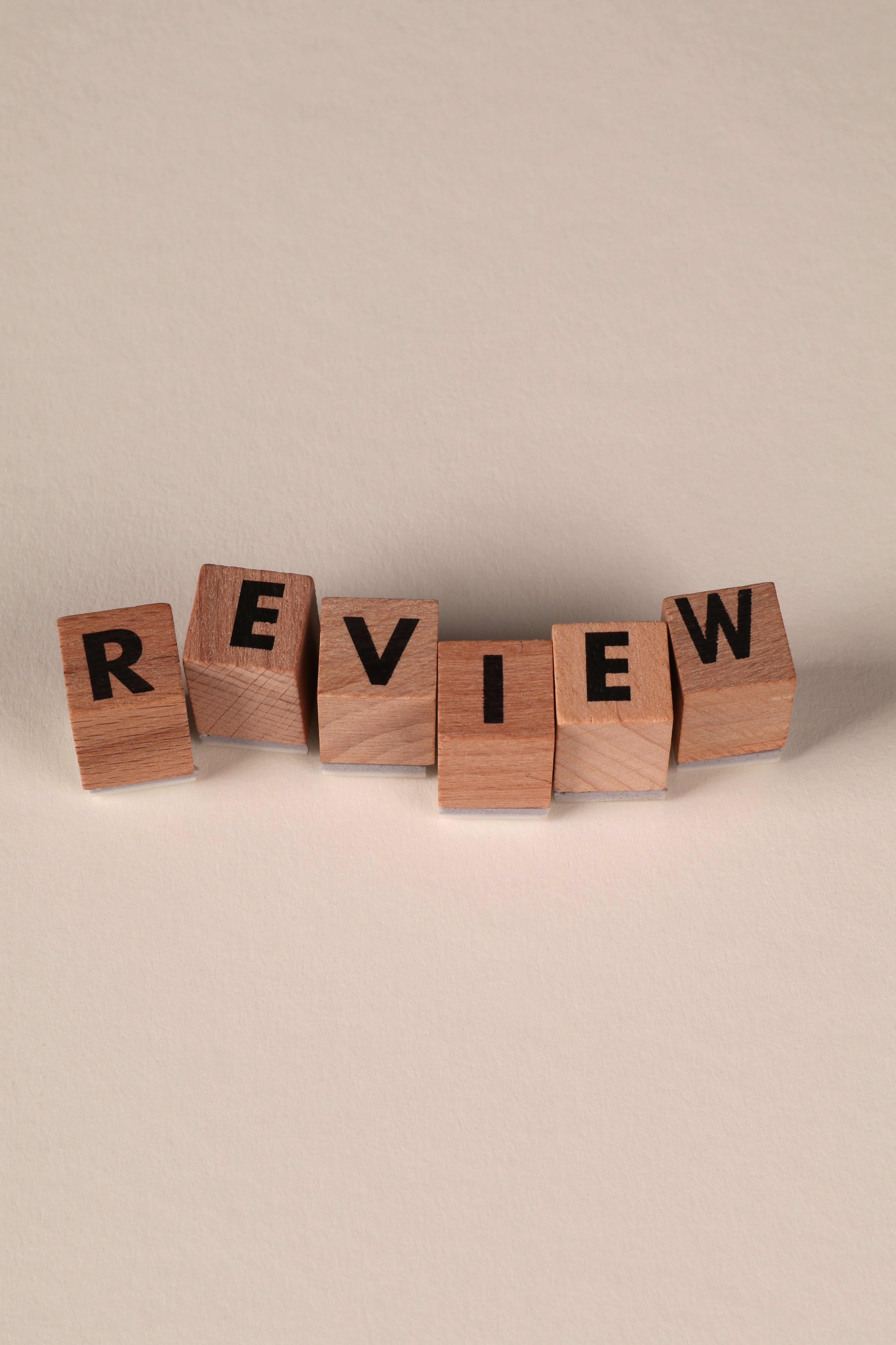 Wooden blocks on a white background spell out "REVIEW"